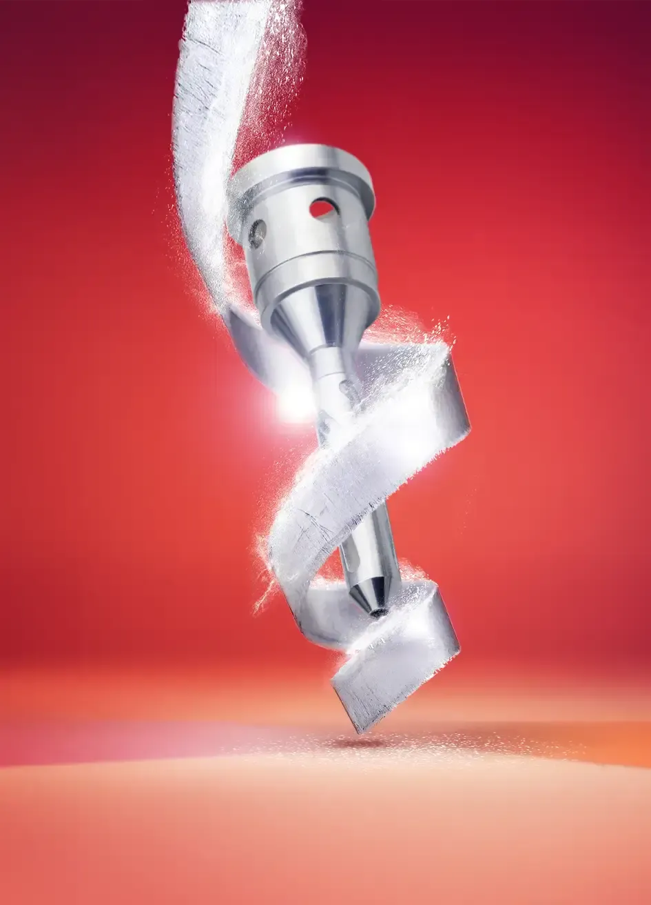 Ein Maschinenteil aus Metall dreht sich und erzeugt ein wirbelndes silbernes Band aus Spänen vor einem leuchtend roten Hintergrund, wobei funkelnde Partikel die Bewegung hervorheben.