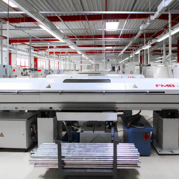 Nahaufnahme einer industriellen CNC-Fräsmaschine, die ein Metallwerkstück schneidet, wobei Metallspäne auf dem Arbeitstisch in einer Werkstatt verstreut sind.