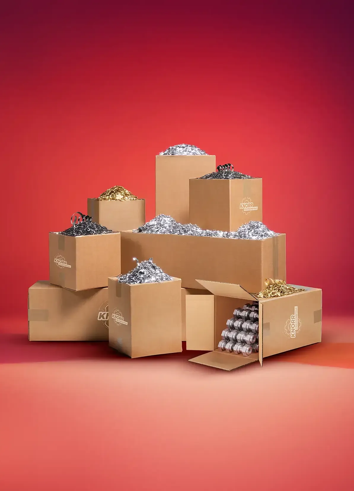 Eine Gruppe von Pappschachteln, einige offen, andere geschlossen, gefüllt mit metallischen Flaschenverschlüssen in Silber, Gold und Schwarz, angeordnet vor einem roten Hintergrund mit Farbverlauf.