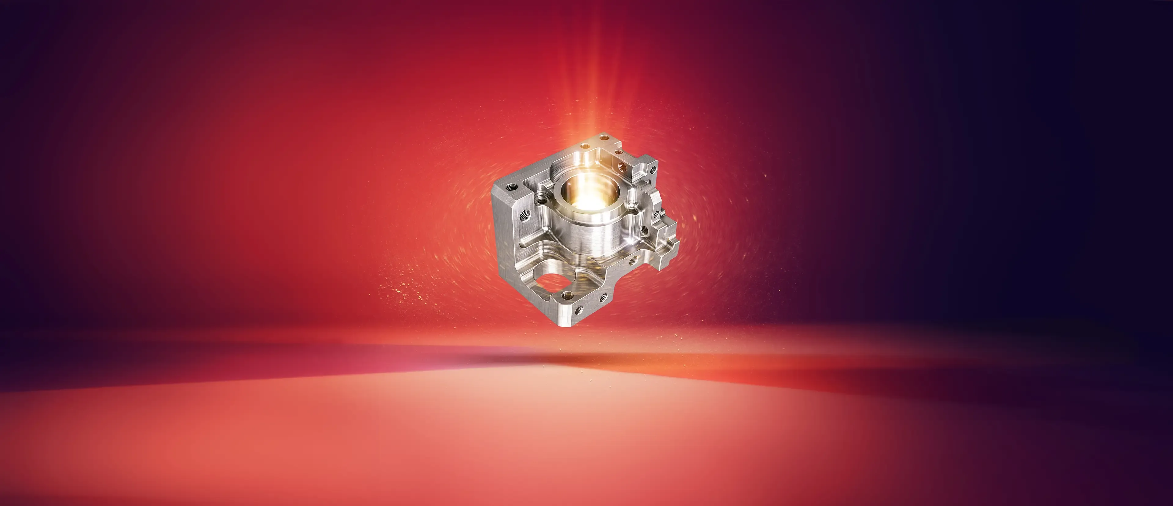 Ein metallisches, präzisionsgefertigtes mechanisches Bauteil schwebt in der Luft vor einem rot-violetten Hintergrund, der von oben mit einem glühenden Licht beleuchtet wird.